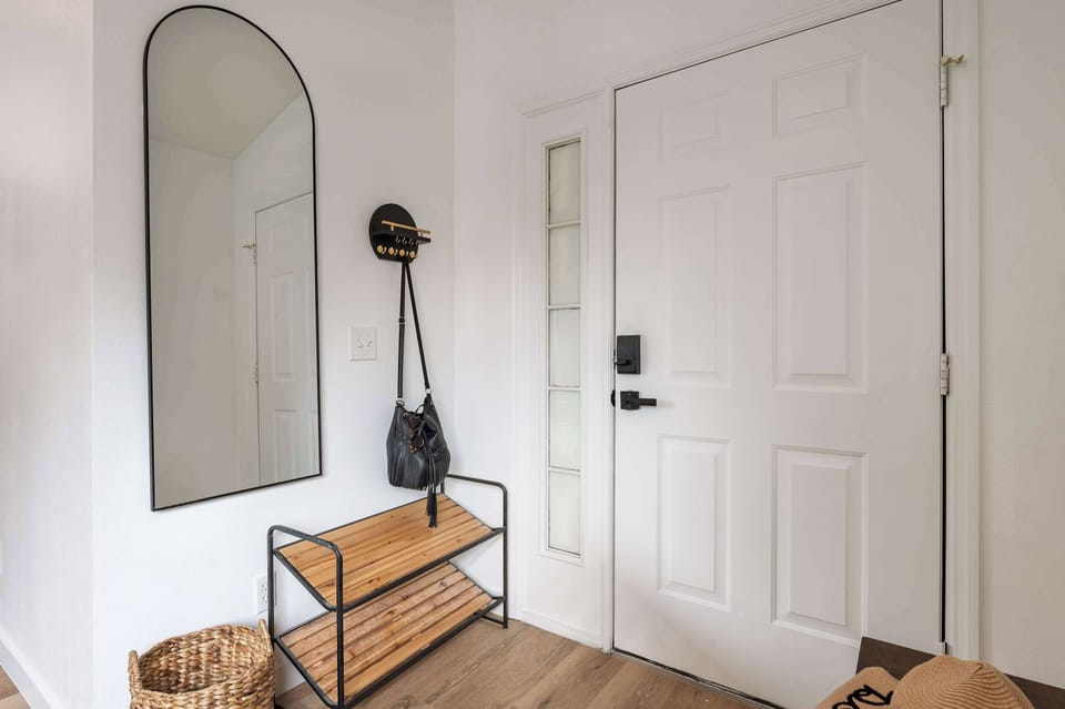 Entryway with a full-length mirror, wooden bench, and wall hooks for convenient storage.