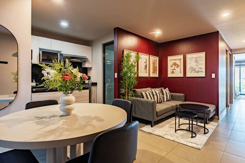Relax in a living room with character — bold color and greenery throughout.