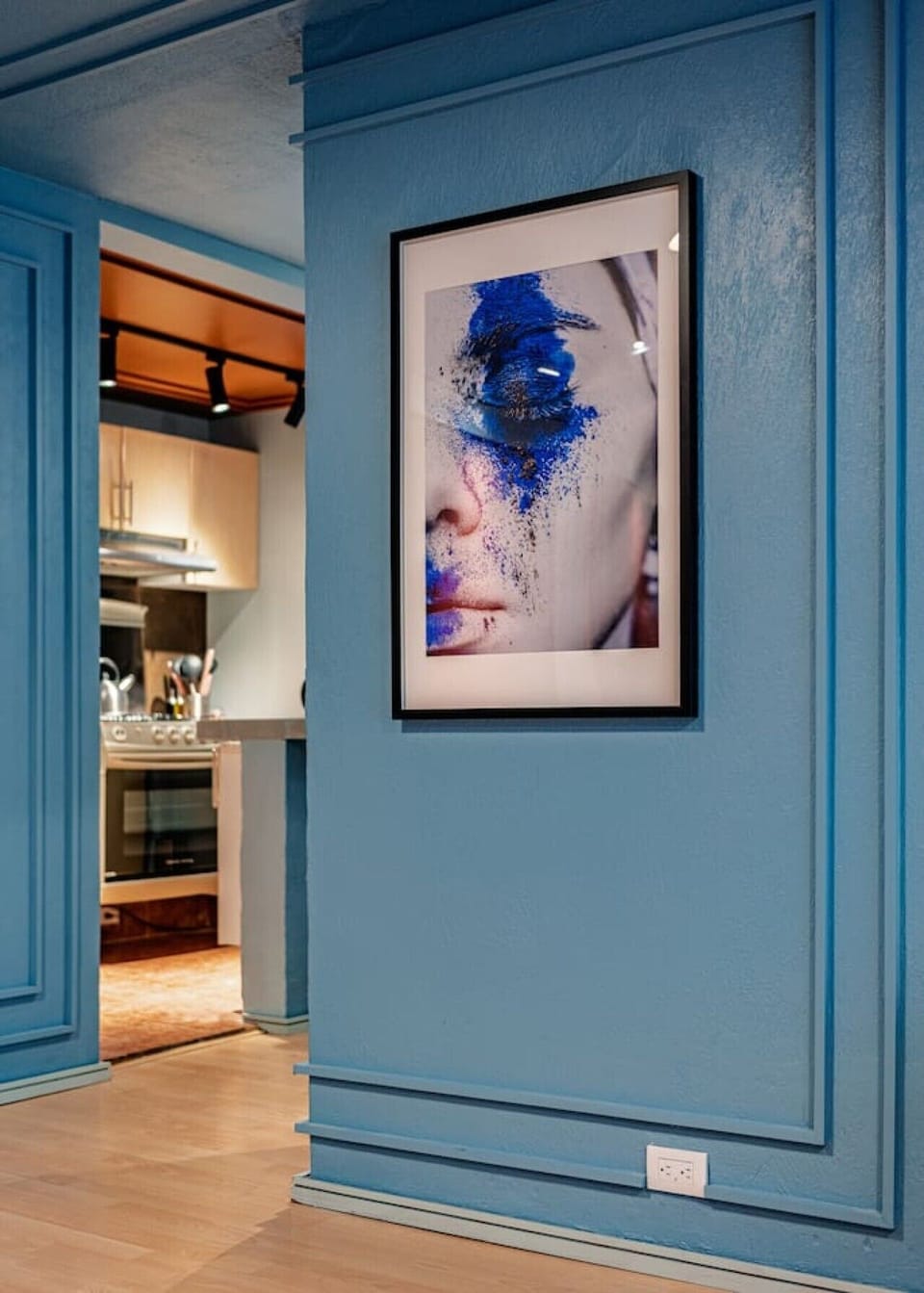 Hallway detail with colorful artwork and a view toward the kitchen.