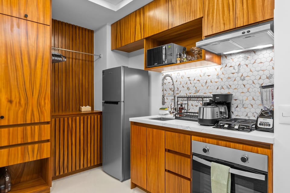 Cook with ease! This premium space features a gas stove, oven, microwave, coffee maker, and blender. Complemented by beautiful geometric tile accents and custom wood closet storage.