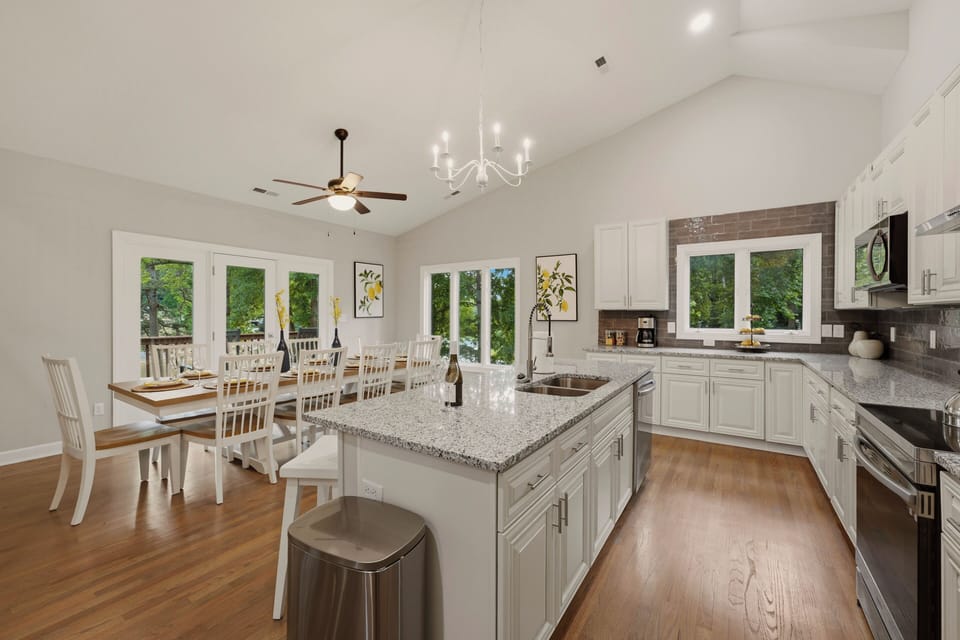A chef's dream kitchen boasting a massive central island with premium granite countertops, crisp white cabinetry, and high-end stainless steel appliances.