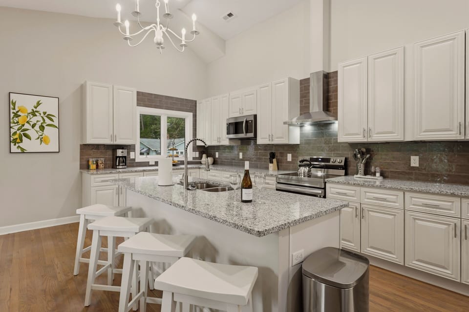 Elegant pendant lighting and a modern range hood perfectly complement the clean lines and meticulous design of the gourmet kitchen.