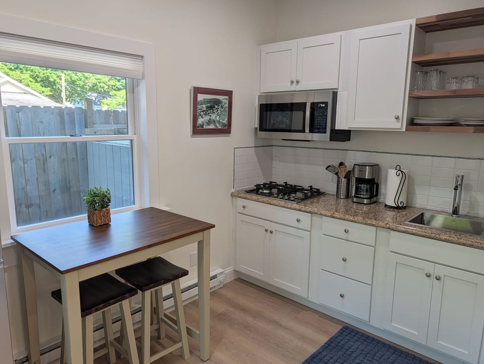 OVERVIEW: The apartment's cute kitchen with a stovetop, microwave, coffeemaker, refrigerator, and other kitchen essentials. Perfect for cooking! The cute dining table to the left offers a place to eat