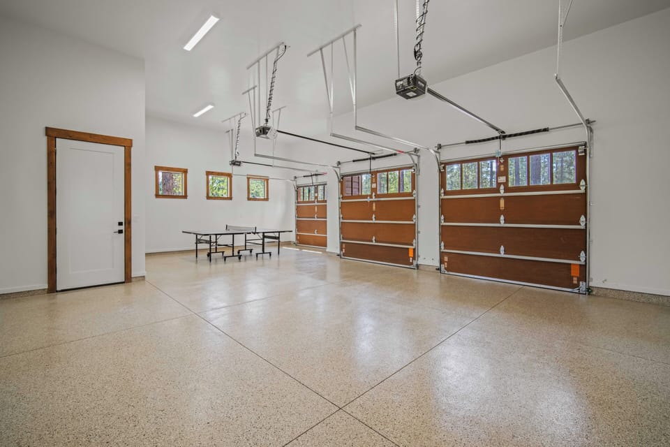 This spacious garage features a pristine floor perfect for parking or recreation, complete with a ping pong table for friendly competition. The bright, clean space offers ample room for your vehicles and activities.