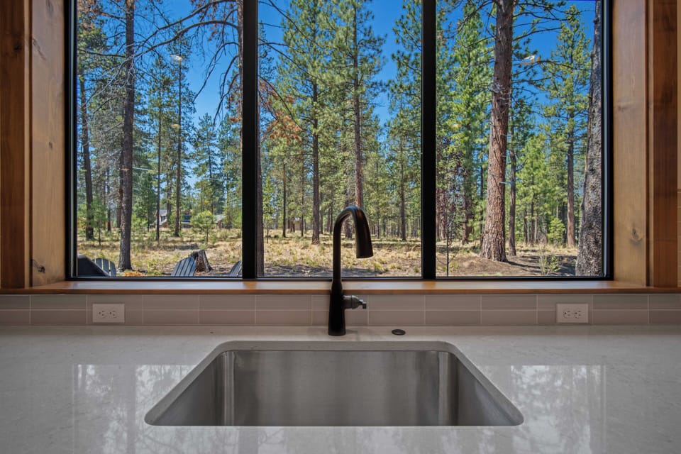 Imagine washing dishes with this serene forest view framing your quiet moments. Sunlight filters through towering pines, bringing the peaceful outdoors right into your kitchen.