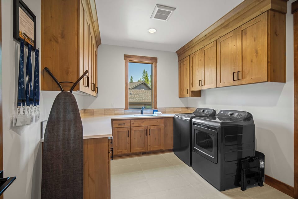 Your dedicated laundry room makes long stays effortless, with full-size washer and dryer, plenty of counter space for folding, and warm wood cabinetry to keep everything organized and within reach.