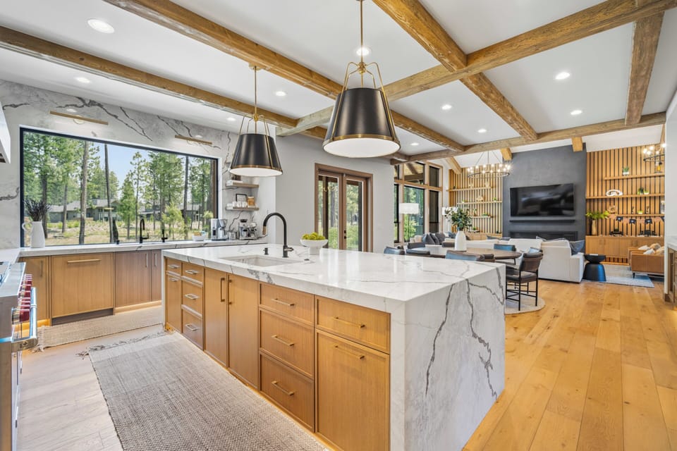 You'll love the open-concept design, where exposed wood beams soar above a chef's kitchen with marble island. Picture yourself preparing meals while gazing at forest views, then relaxing in the living area with a cozy fireplace.