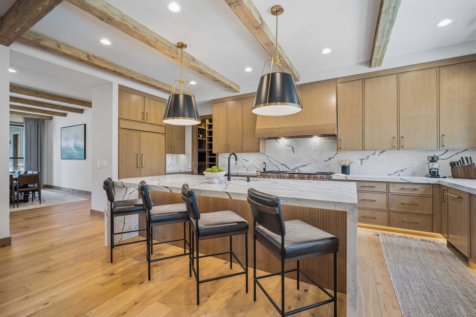 Step into a beautifully designed kitchen featuring soaring vaulted ceilings with rustic beams, elegant marble countertops, and a spacious island perfect for gathering with loved ones.