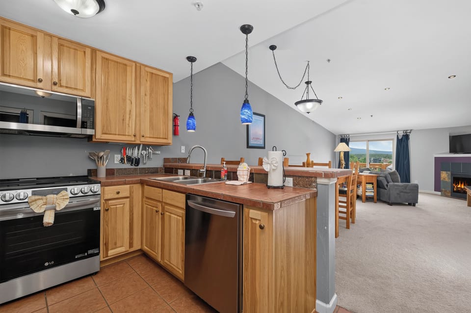 You'll love the open layout blending your fully equipped kitchen, cozy dining space, and living area—perfect for cooking together, sharing meals, and relaxing by the fire with stunning mountain views just beyond your windows.
