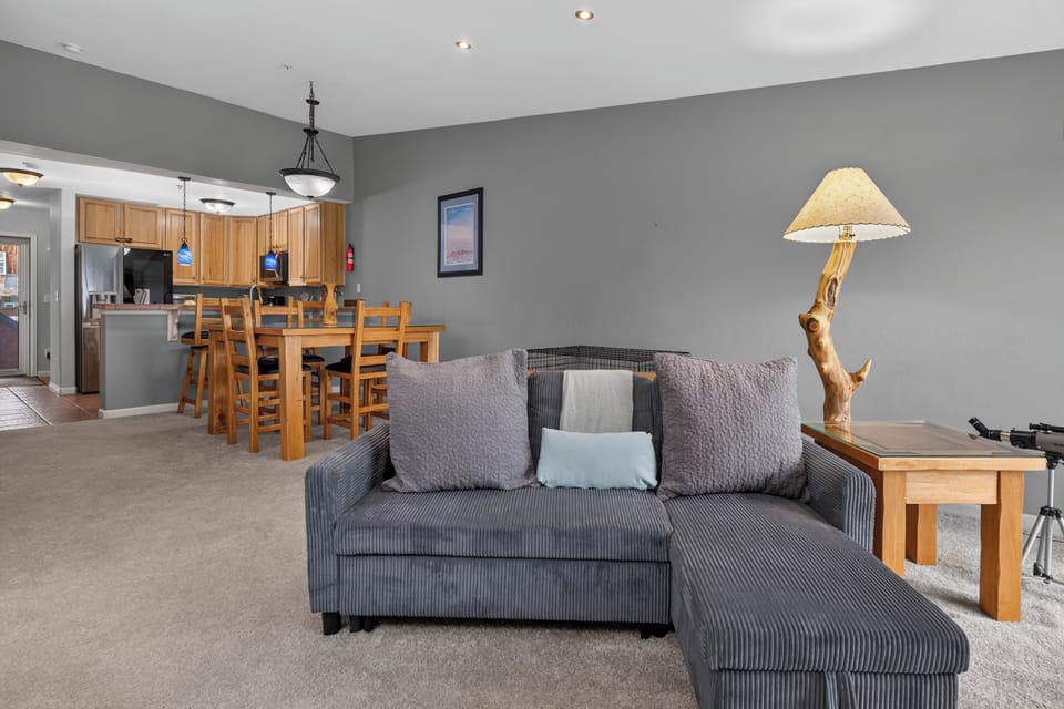 Sink into the plush sectional as natural light flows through this open-concept living space, where cozy evenings blend seamlessly with casual dining and home-cooked meals in your fully equipped kitchen.