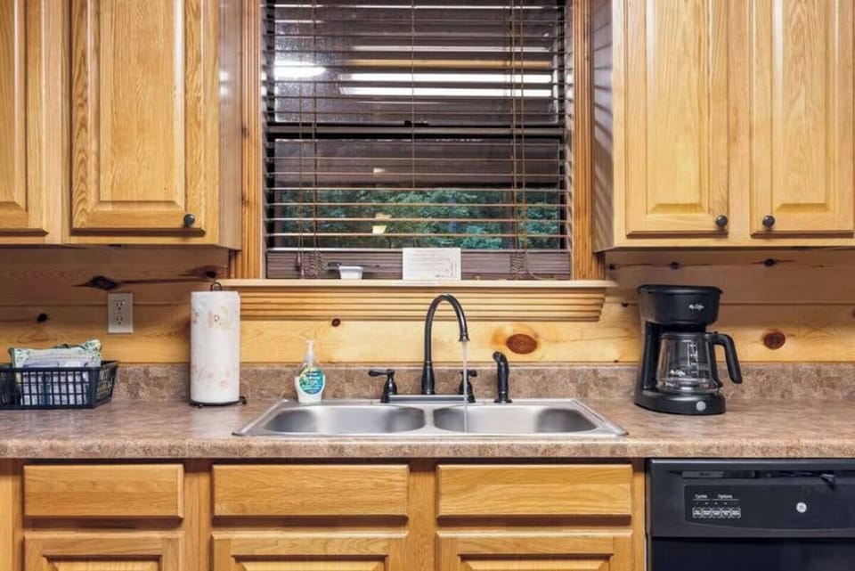 You'll love cooking in this bright, fully equipped kitchen with warm wood cabinetry, ample counter space, and a sunny window overlooking peaceful greenery outside.