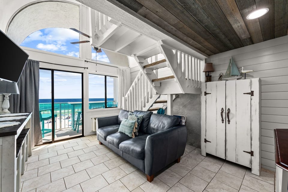 Coastal retreat with floor-to-ceiling glass doors framing turquoise waves. Rustic wood ceilings and whitewashed walls create beachy-chic charm, while the private balcony offers the perfect ocean-view morning coffee spot.