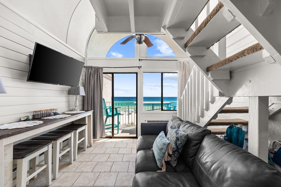 Relax on your plush leather sofa while gazing at the stunning turquoise waters through your glass balcony doors. The open, airy loft-style space invites you to unwind with beachy coastal charm and modern comfort.