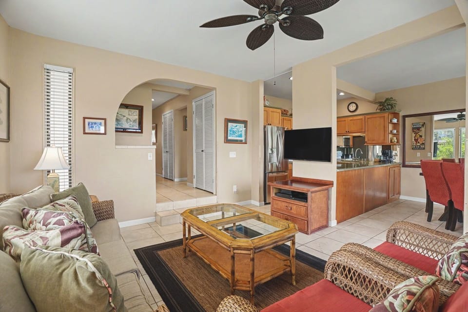Relax in your spacious living area with comfortable tropical seating, ceiling fan, and flat-screen TV. The open floor plan flows seamlessly into the full kitchen, perfect for your island getaway.