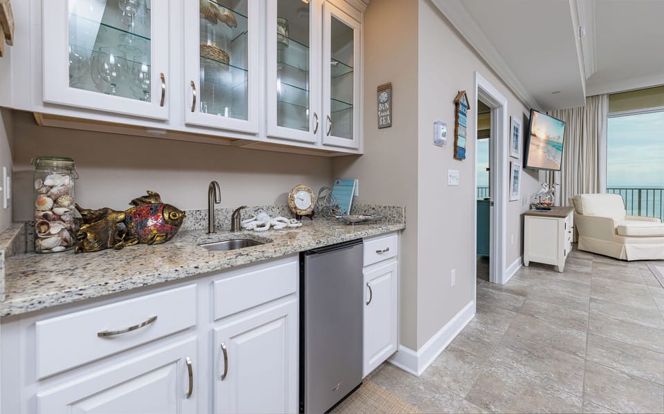 A wet bar offers a cool sip as you unwind and listen to waves beyond the living room's cozy chair