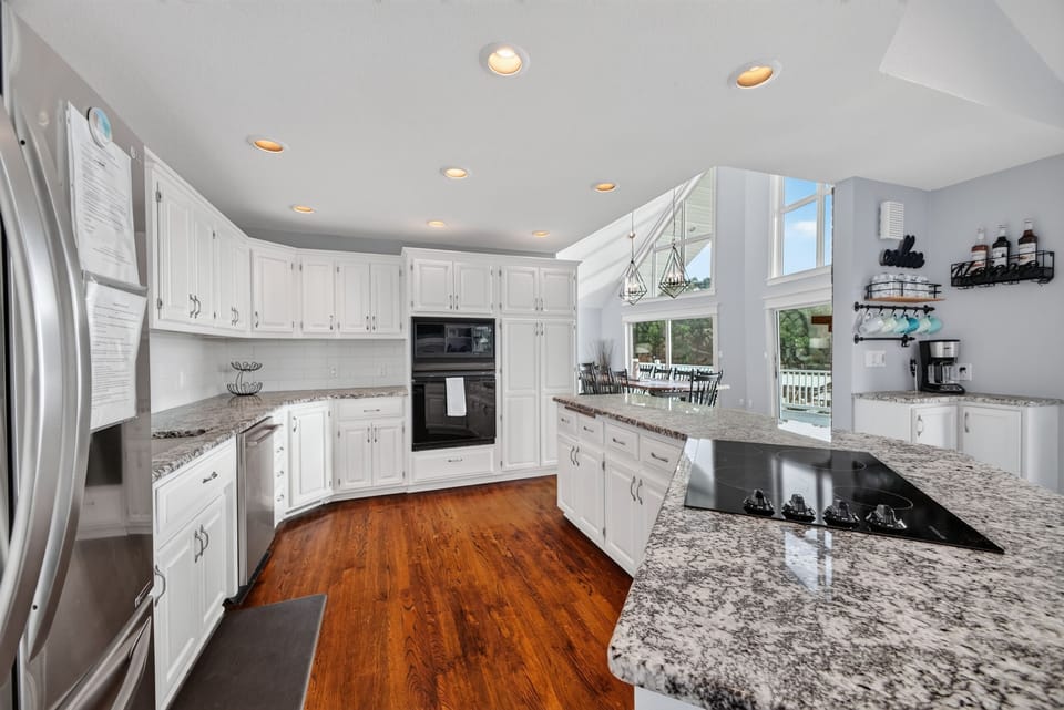 Your chef's kitchen awaits—gleaming granite counters, sleek white cabinetry, and modern appliances make every meal a joy. Natural light pours in while you cook, creating a bright and airy space.