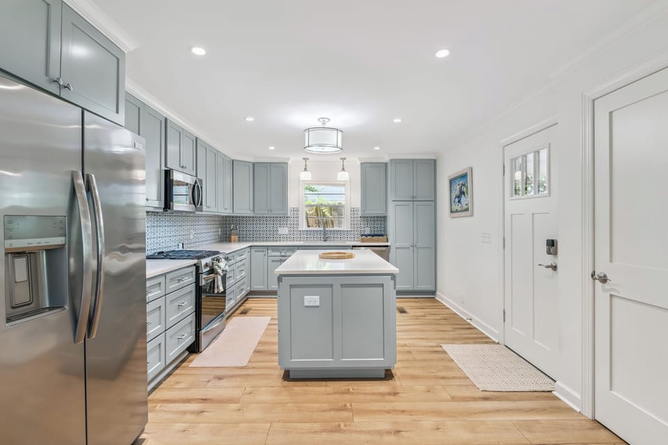 Step into your beautifully designed kitchen with soft gray cabinetry, sleek stainless appliances, and a center island perfect for meal prep or morning coffee.