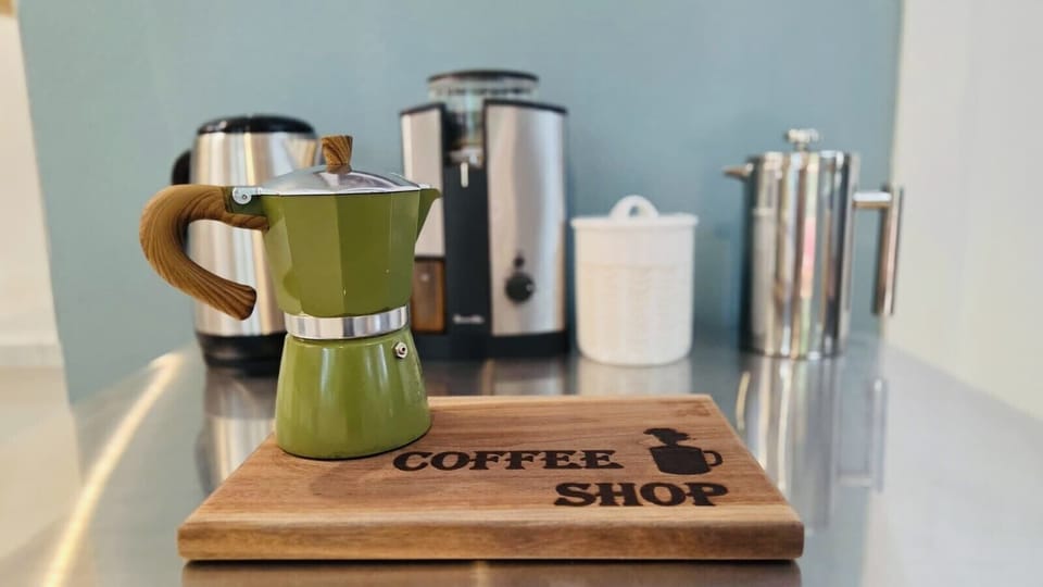 Fully equipped coffee station with a coffee grinder, French press, and electric kettle.