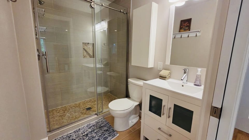 Spacious bathroom featuring a glass walk-in shower and contemporary finishes.