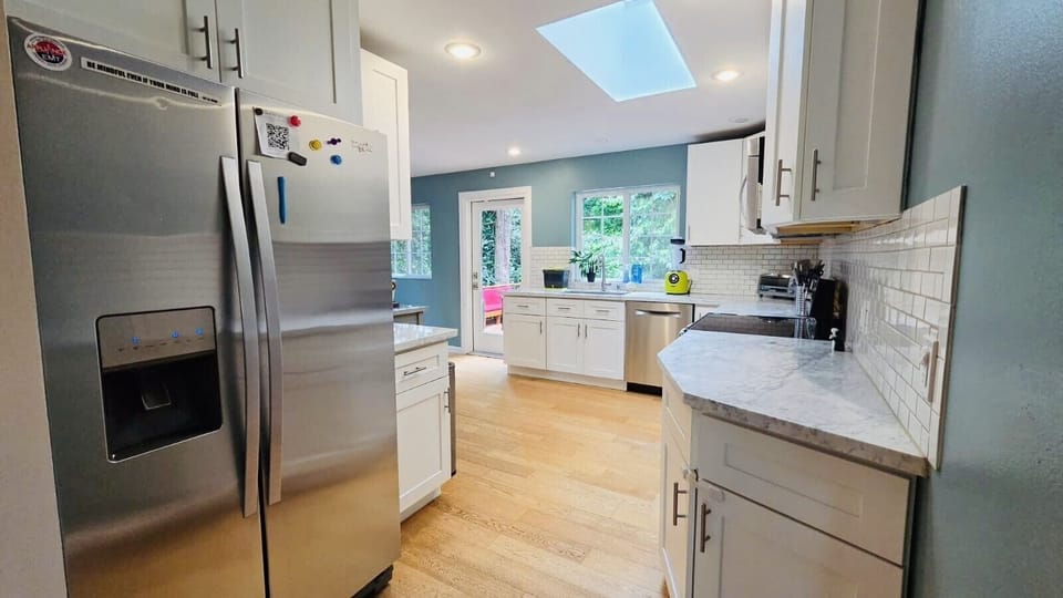 Modern kitchen with stainless steel appliances, spacious counters, and a skylight for natural light.
