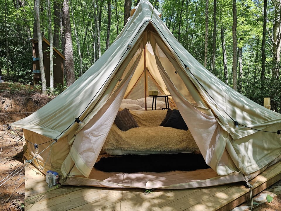 Relax on the loveseat beneath towering hardwoods before settling into your luxury canvas retreat.