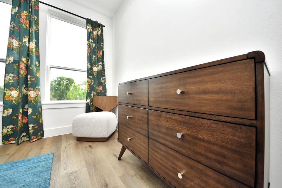 Bright bedroom corner with stylish dresser, cozy chair, and sunny window