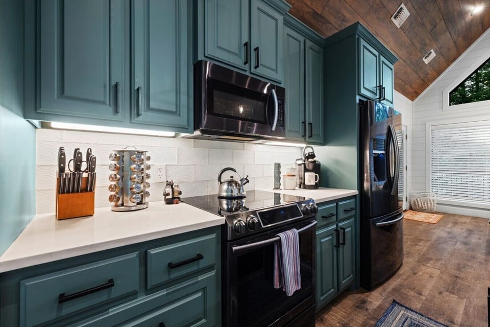 Fully stocked kitchen with stainless appliances and bold cabinet color.