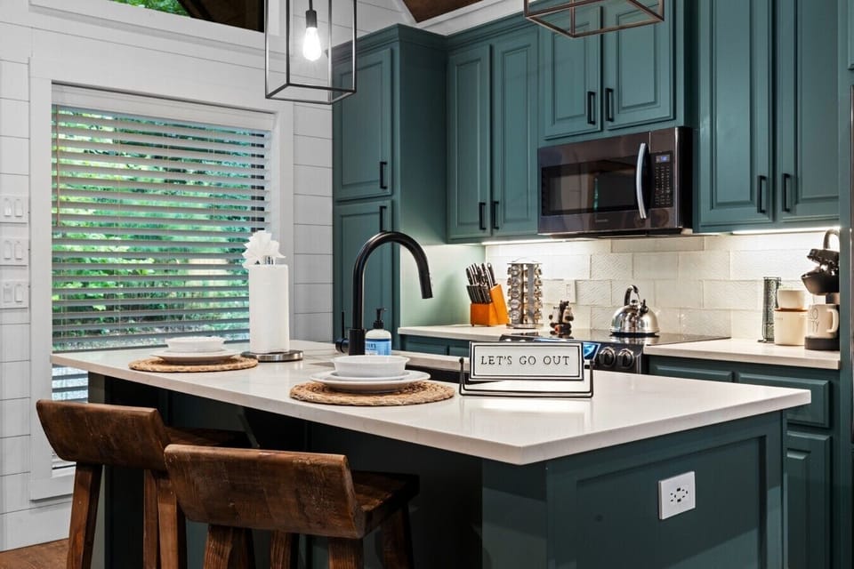 Bright kitchen sink and prep space with green cabinetry.