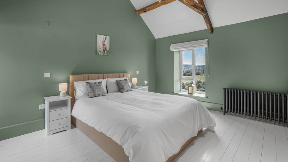 The master bedroom is spacious with high ceilings, exposed wooden beams, king-size bed and wonderful views of the vineyard