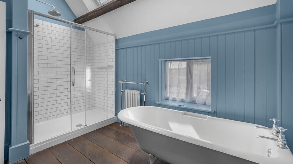 The  spacious bathroom has a roll-top bath and large shower