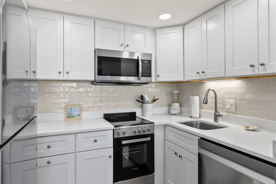 Cook with ease in a bright, modern cooking space featuring a stylish tile backsplash.