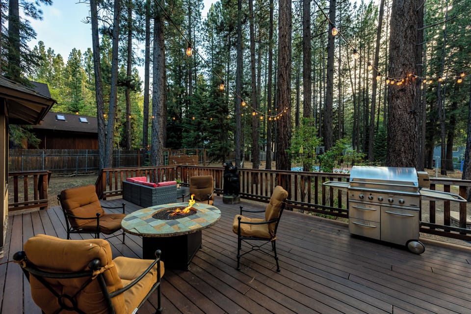 Gather around the glowing fire pit on your private deck, where string lights twinkle through towering pines. The hot tub bubbles nearby while the grill awaits your evening feast.