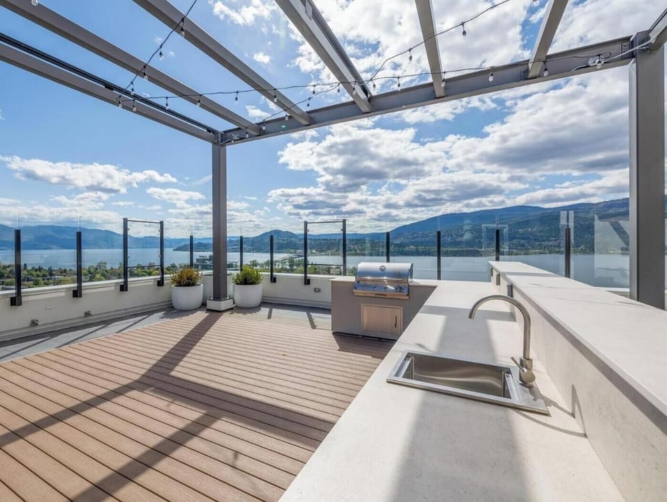 Public rooftop terrace with BBQs, kitchen sinks, seating, and lounge chairs