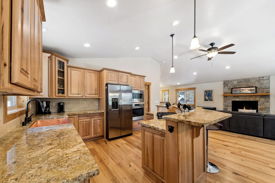 Gather in your gourmet kitchen with granite counters, stainless appliances, and an open layout flowing to the living area with stone fireplace—perfect for cooking and connecting.