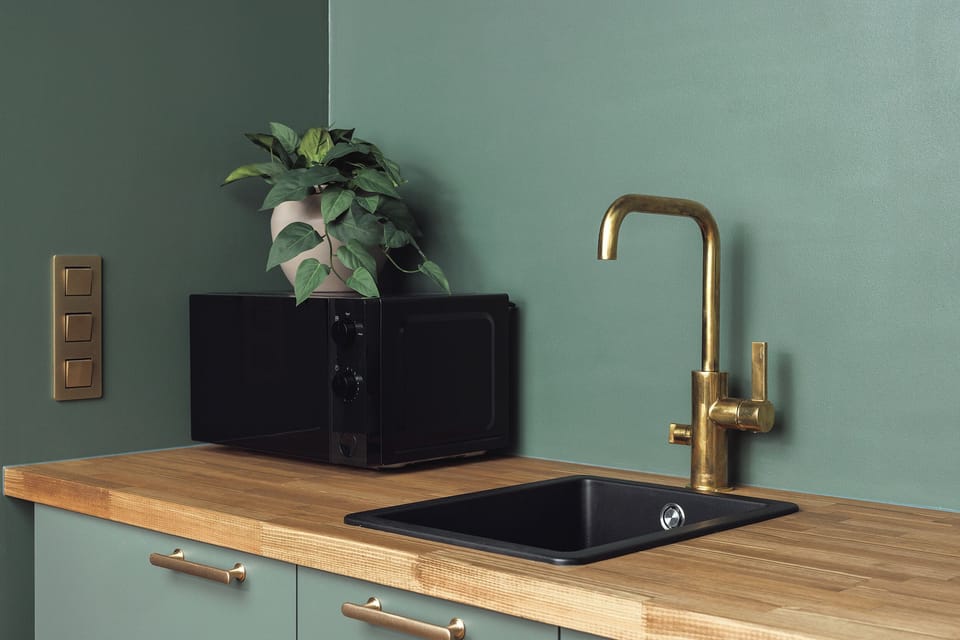 Stylish kitchenette with brass fixtures, wood counters, and modern design