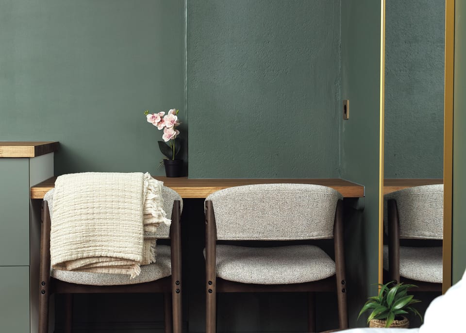 Chic green-toned vanity nook with cozy seating and full-length mirror