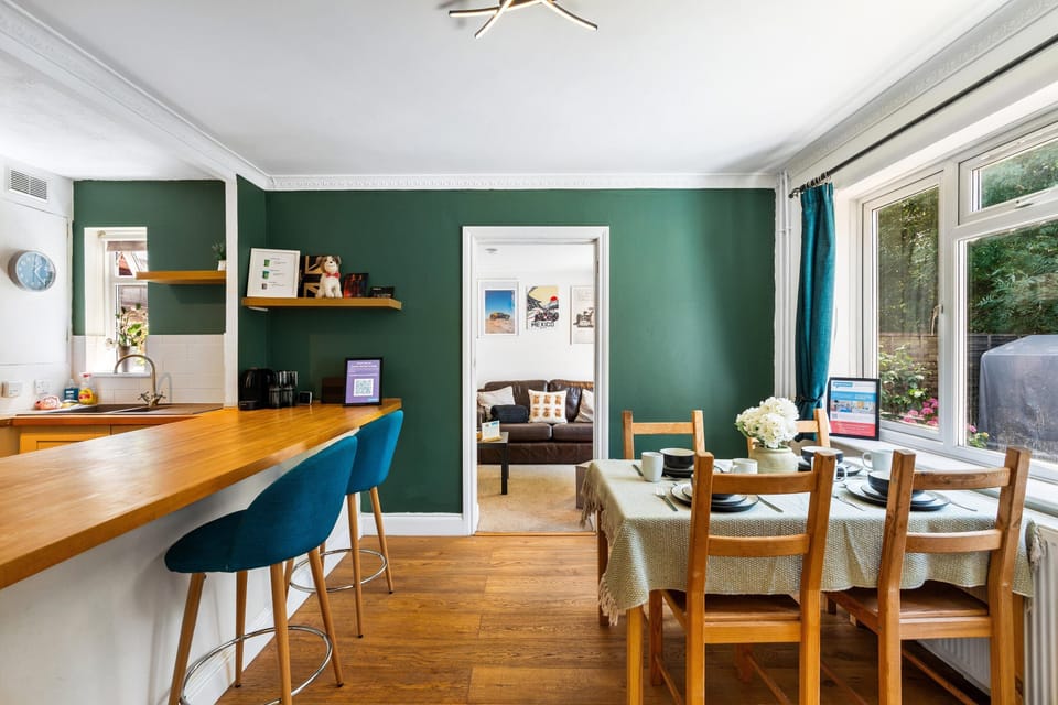 Bright open-plan living space featuring a fully equipped kitchen, dining table and cosy lounge overlooking the garden
