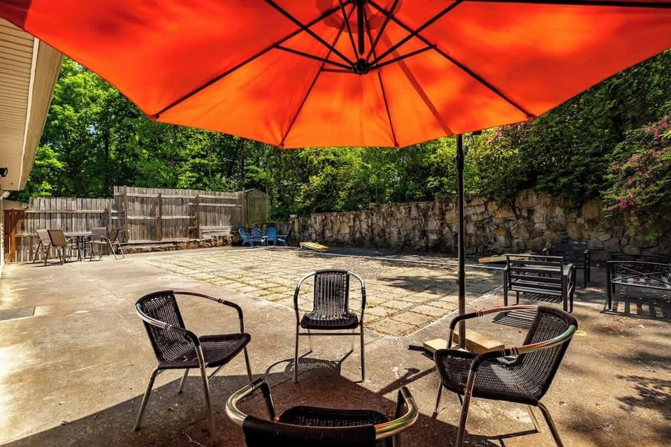 Gather on the spacious patio beneath the oversized umbrella for morning coffee, evening cocktails, or outdoor dining while enjoying Songbird Estate's private wooded setting.
