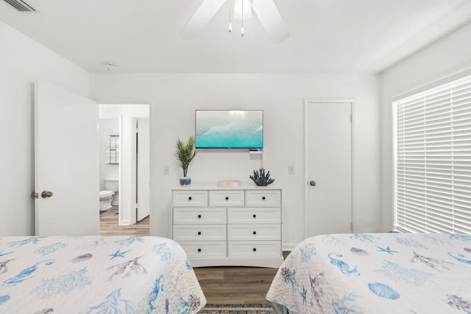 Guest bedroom with two full beds, Smart TV, and a relaxed beach-house atmosphere.