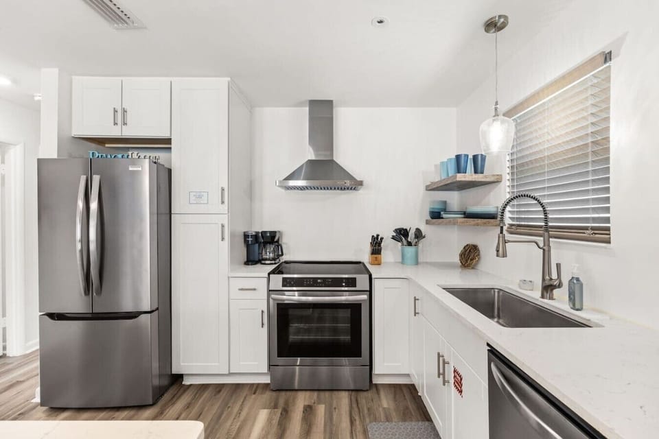 Modern beach house kitchen featuring stainless appliances and open shelving for a clean coastal feel.