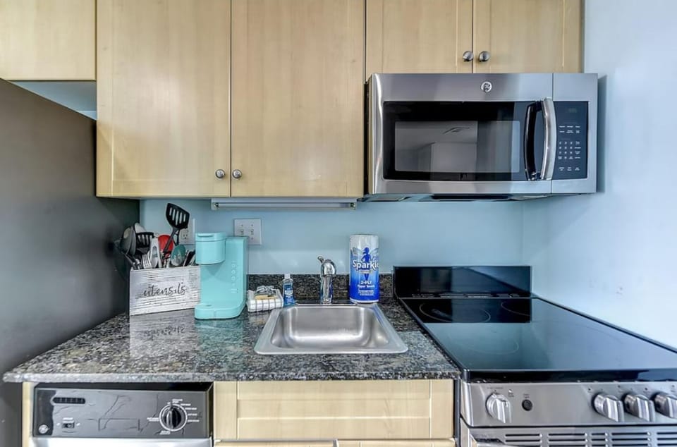 Kitchen sink and countertop with microwave, coffee maker, and cooktop appliances