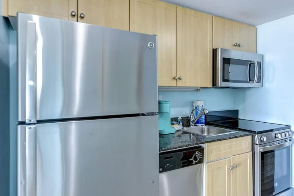 Fully equipped kitchen featuring stainless steel fridge & modern cabinets.