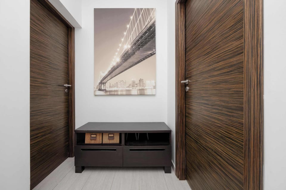A hallway with wooden doors, a small bench, and a decorative wall picture. The bright interior has a clean and modern design.