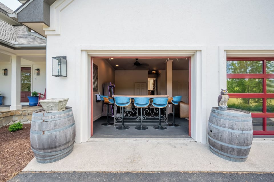 Unique indoor-outdoor entertainment space featuring bar seating, a classic arcade game, and an open garage-style layout.
