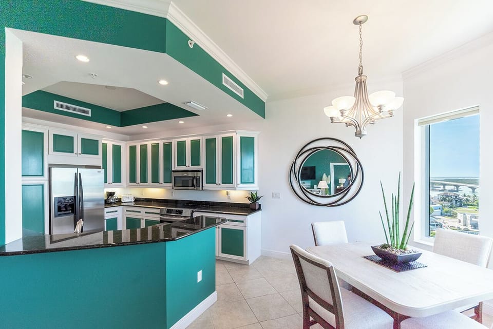 Bright and Airy Dining Area and Open-Concept Kitchen has a dining table for 4 and a classic chandelier. Both the Kitchen and the Dining Area enjoy a large window showcasing an expansive water view.