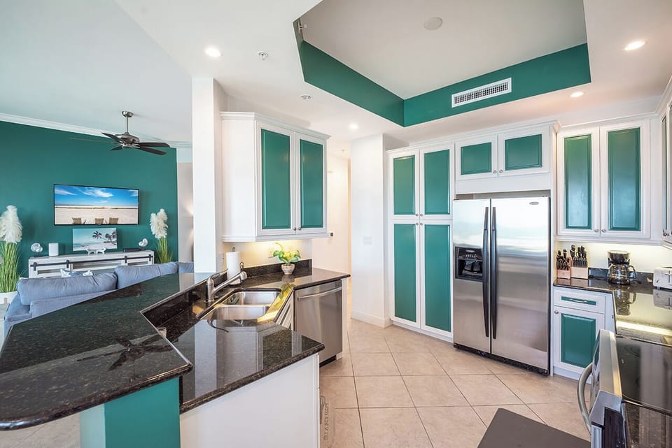 Modern Kitchen featuring granite countertops, stainless steel appliances (including a large refrigerator), and a breakfast bar overlooking the living area.