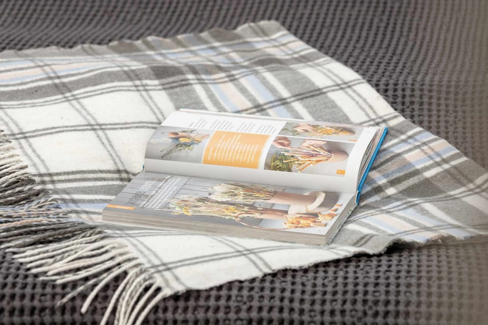 A folded blanket on the bed is topped with magazines and reading material, creating a welcoming touch for guests. The patterned bedding adds texture to the room.