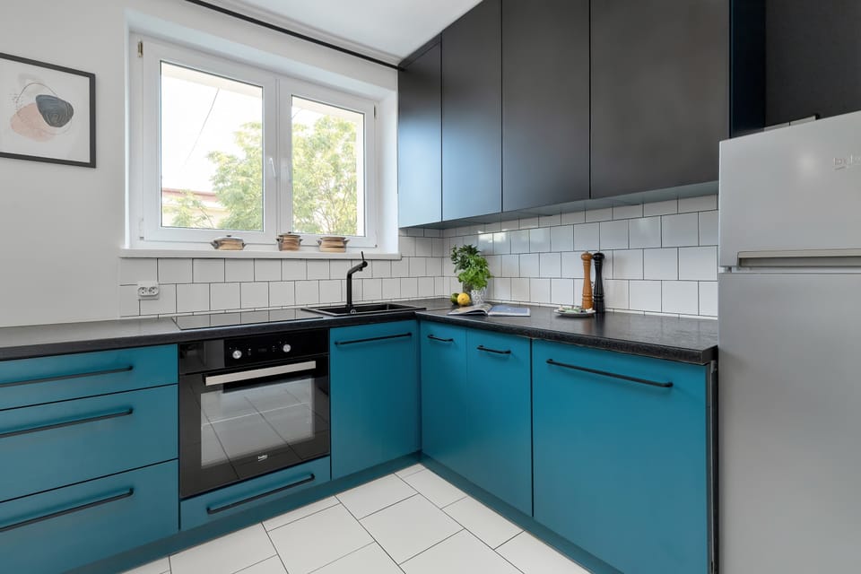 Another perspective of the kitchen showcases generous countertops, turquoise cabinetry, and built-in appliances. The practical layout is designed for convenient meal preparation.