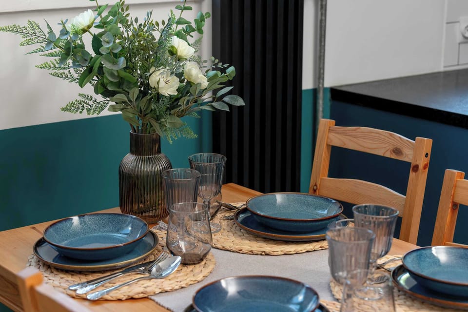 A close-up of the dining table highlights neatly arranged table settings, glassware, and a floral centerpiece. Decorative details create a warm dining atmosphere.