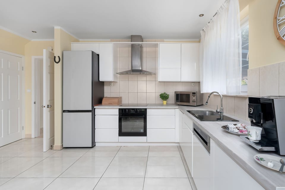 A contemporary kitchen featuring white cabinets, built-in appliances, and a streamlined design. The space combines practicality with elegance.